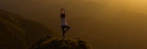 Woman stretching on a mountain top at sunrise