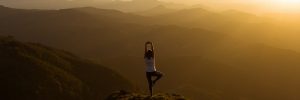 Woman stretching on a mountain top at sunris